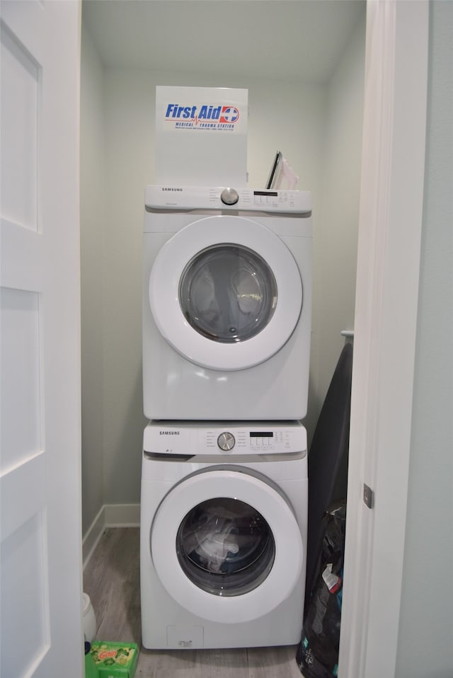 laundry room featuring wood-type flooring and stacked washer / drying machine