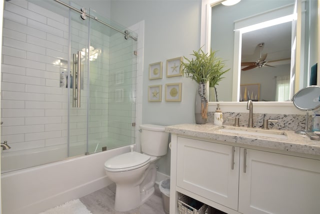 full bathroom featuring enclosed tub / shower combo, toilet, vanity, ceiling fan, and hardwood / wood-style floors