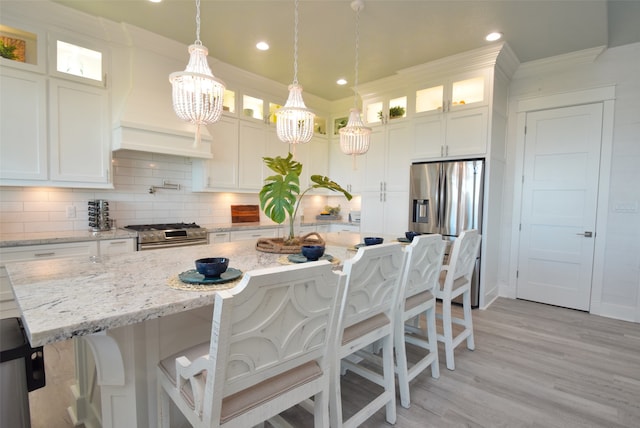 kitchen featuring appliances with stainless steel finishes, light hardwood / wood-style flooring, backsplash, a center island, and white cabinetry