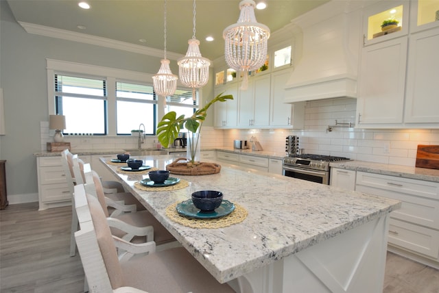 kitchen featuring light hardwood / wood-style floors, gas range, a kitchen island, and custom range hood