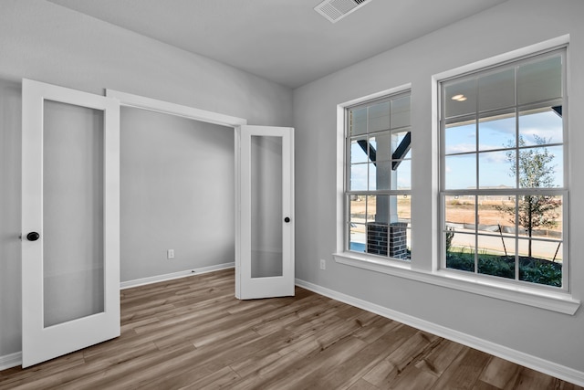 unfurnished bedroom with french doors and hardwood / wood-style flooring