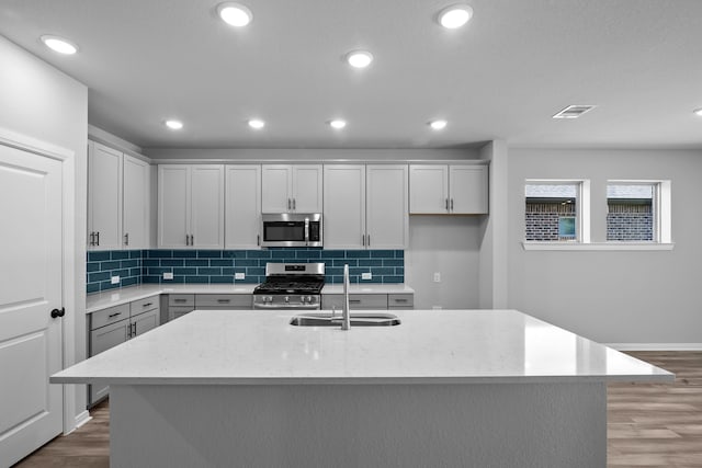 kitchen featuring a center island with sink, hardwood / wood-style flooring, sink, and appliances with stainless steel finishes