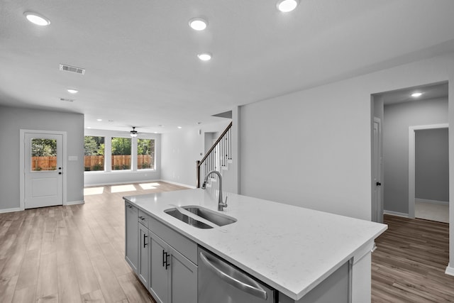 kitchen with dishwasher, a kitchen island with sink, sink, light hardwood / wood-style flooring, and ceiling fan