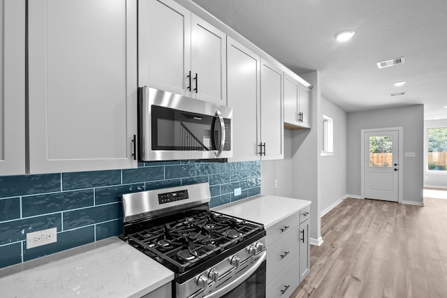 kitchen featuring white cabinets, stainless steel appliances, and light hardwood / wood-style flooring