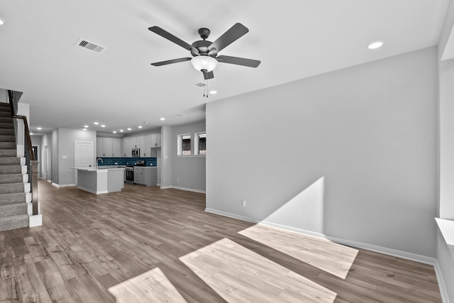 unfurnished living room with ceiling fan, sink, and light hardwood / wood-style flooring