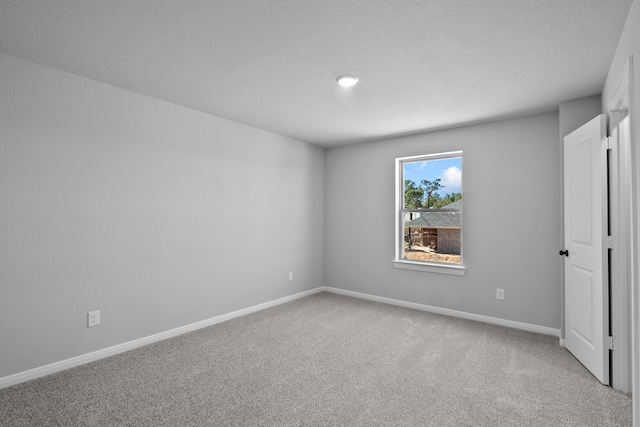 empty room with carpet floors and a textured ceiling