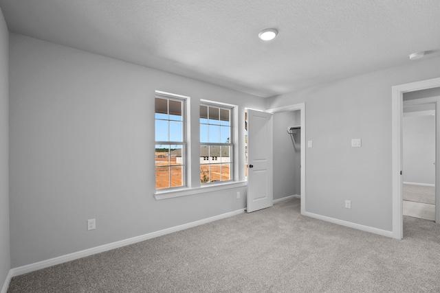 unfurnished bedroom featuring light carpet, a textured ceiling, and a closet