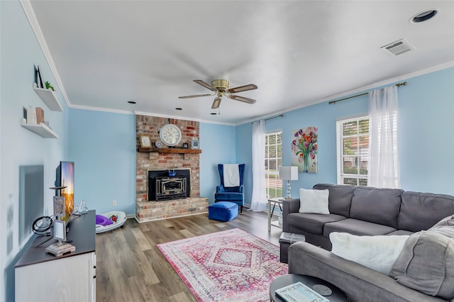 living room featuring light wood-type flooring, a wood stove, and ornamental molding