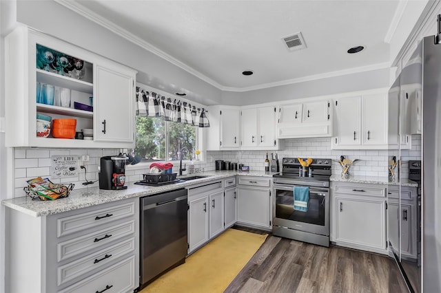 kitchen with white cabinets, hardwood / wood-style floors, stainless steel appliances, and crown molding