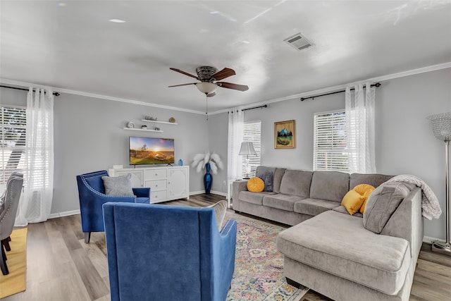 living room featuring light hardwood / wood-style floors, ornamental molding, and a wealth of natural light