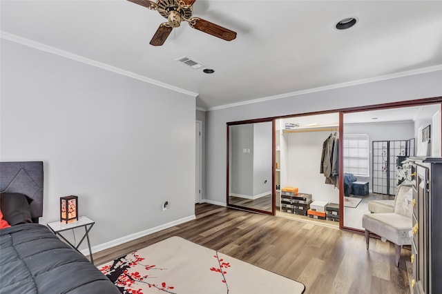 bedroom featuring ceiling fan, wood-type flooring, ornamental molding, and a closet