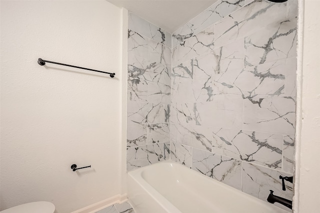 bathroom featuring tiled shower / bath and toilet