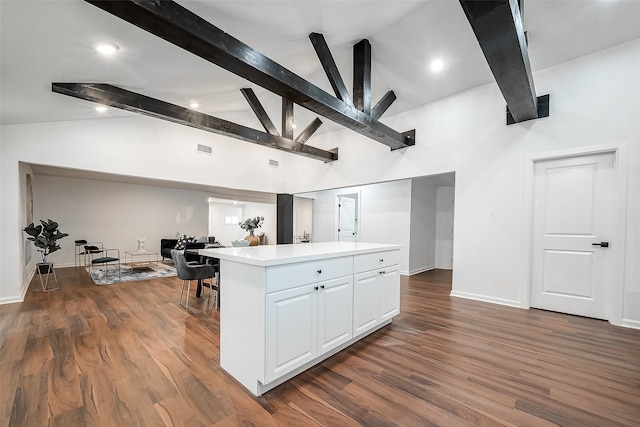 kitchen with white cabinets, vaulted ceiling with beams, dark hardwood / wood-style floors, and a kitchen island