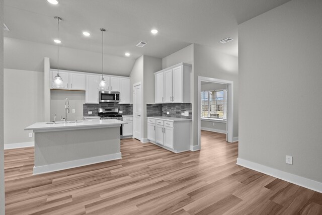 kitchen featuring visible vents, white cabinets, a sink, stainless steel appliances, and backsplash