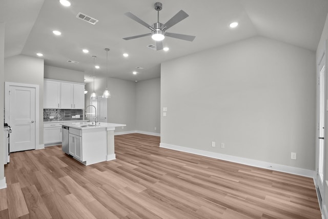 kitchen with a center island with sink, light countertops, visible vents, a sink, and dishwasher