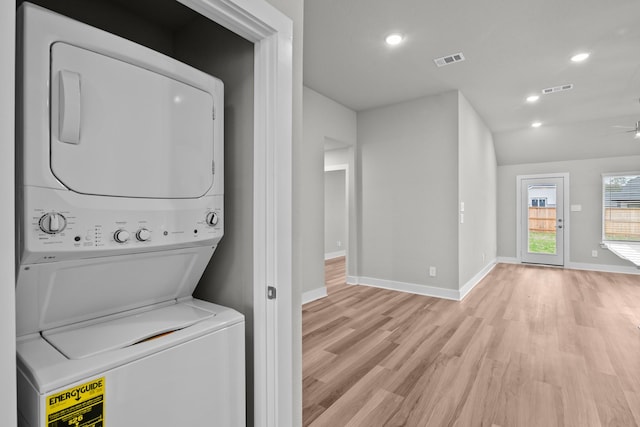 clothes washing area featuring light wood-type flooring, stacked washer / dryer, laundry area, and visible vents