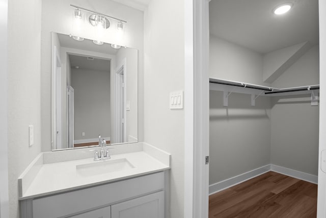 bathroom featuring a spacious closet, baseboards, wood finished floors, and vanity