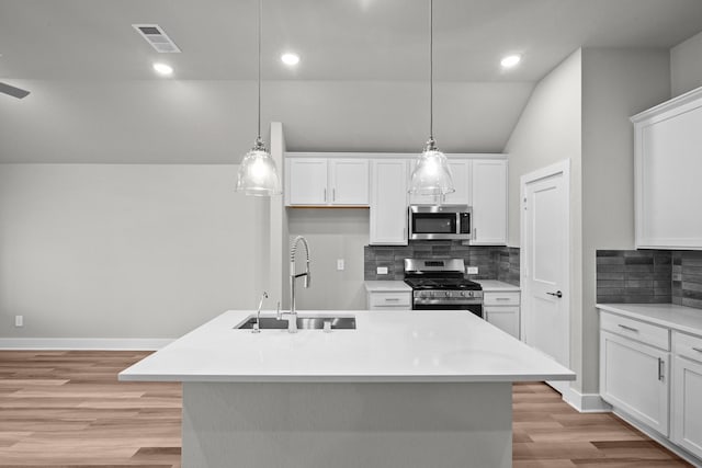 kitchen with light wood finished floors, visible vents, appliances with stainless steel finishes, white cabinetry, and a sink