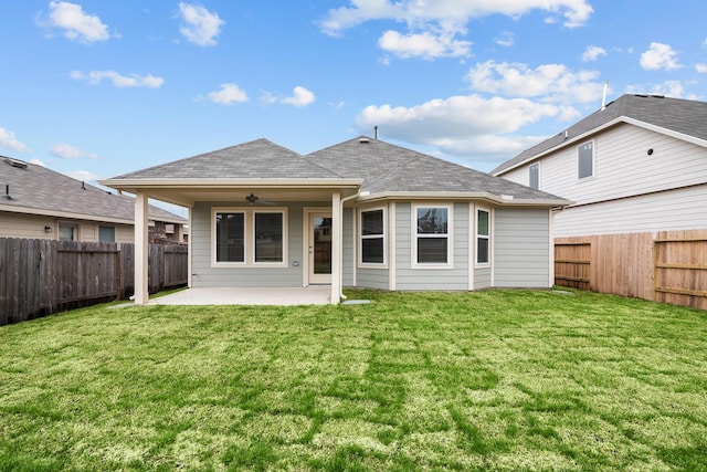 rear view of house featuring ceiling fan, a fenced backyard, roof with shingles, a lawn, and a patio area