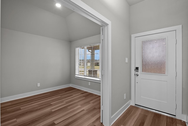 foyer entrance with baseboards, vaulted ceiling, and wood finished floors