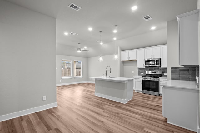 kitchen with decorative backsplash, appliances with stainless steel finishes, open floor plan, light countertops, and a sink