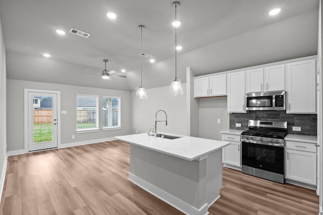 kitchen with a sink, visible vents, white cabinets, appliances with stainless steel finishes, and decorative backsplash