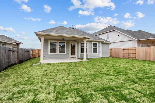 back of property with a fenced backyard, a shingled roof, a lawn, and a patio