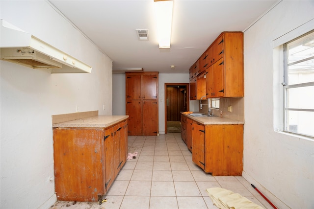 kitchen featuring sink, a wealth of natural light, light tile patterned floors, and backsplash