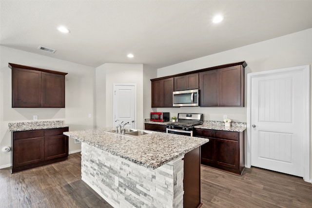 kitchen with a kitchen island with sink, dark wood-type flooring, and appliances with stainless steel finishes