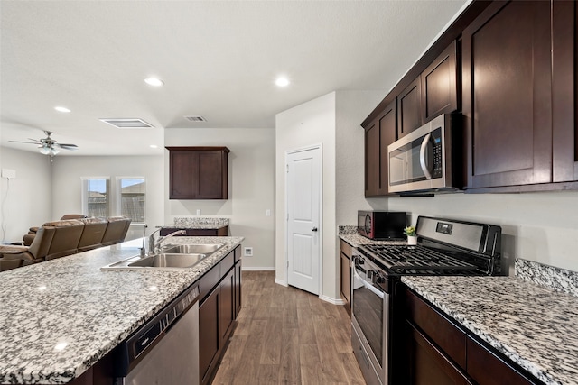 kitchen with light wood-type flooring, light stone counters, ceiling fan, stainless steel appliances, and sink