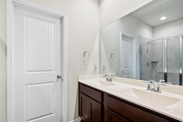 bathroom featuring a shower with door and dual bowl vanity