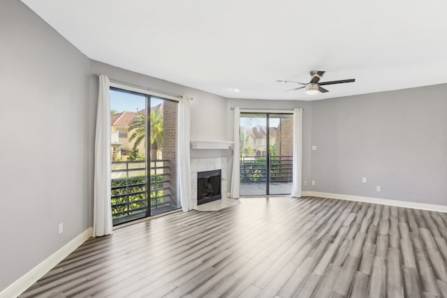 unfurnished living room featuring a healthy amount of sunlight, a tile fireplace, light wood-type flooring, and ceiling fan