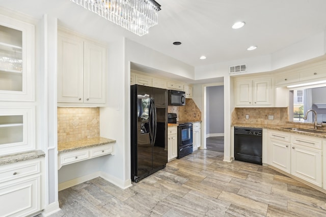 kitchen with decorative backsplash, sink, black appliances, light stone countertops, and a notable chandelier