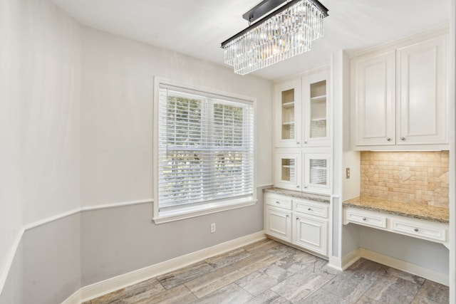 interior space with light hardwood / wood-style floors, a notable chandelier, and built in desk