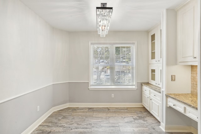 unfurnished dining area featuring a chandelier and light wood-type flooring