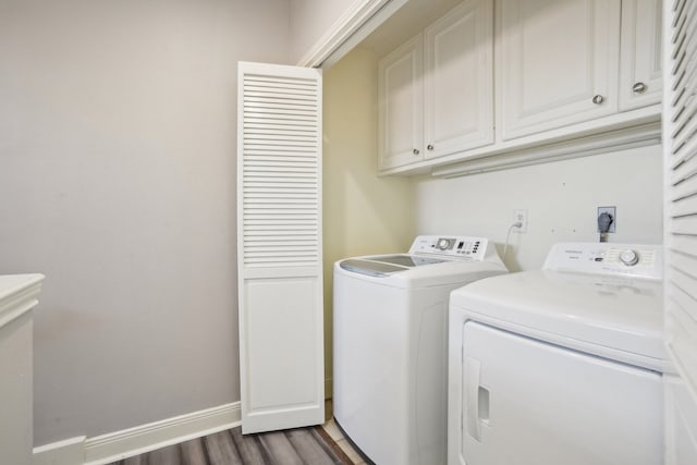 laundry area with washing machine and clothes dryer, dark hardwood / wood-style floors, and cabinets