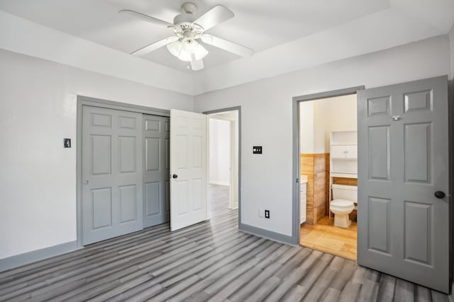 unfurnished bedroom featuring a closet, ceiling fan, ensuite bath, and hardwood / wood-style floors