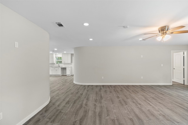 unfurnished living room with hardwood / wood-style flooring, sink, and ceiling fan