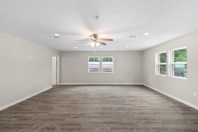 empty room with a healthy amount of sunlight, visible vents, and wood finished floors