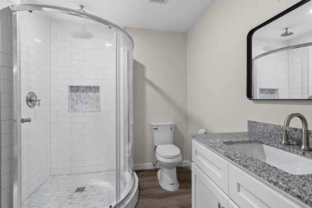 bathroom with toilet, wood finished floors, vanity, baseboards, and a shower stall