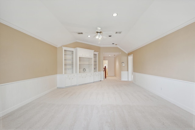 carpeted empty room with ceiling fan, built in features, crown molding, and lofted ceiling