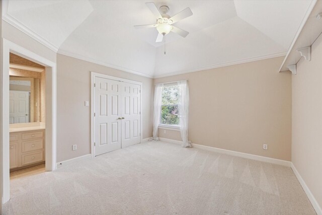 unfurnished bedroom with light carpet, crown molding, lofted ceiling, a closet, and ceiling fan