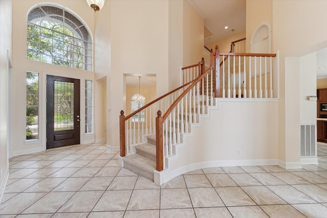 entrance foyer featuring a notable chandelier, a towering ceiling, and light tile patterned floors