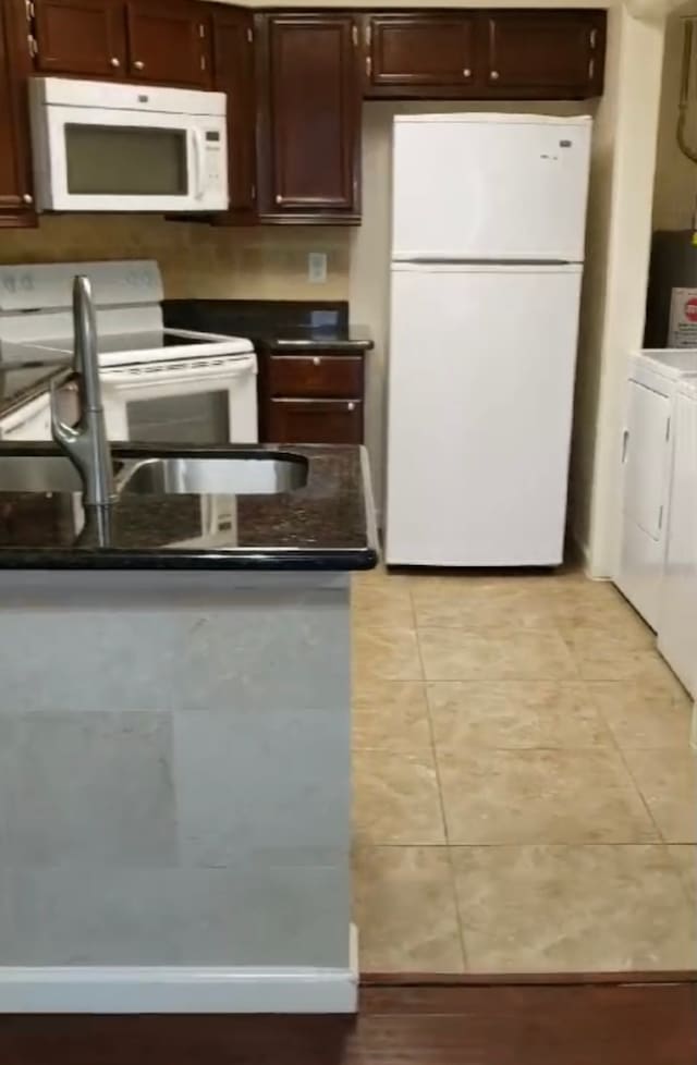 kitchen featuring washer and dryer, white appliances, light tile patterned flooring, and water heater