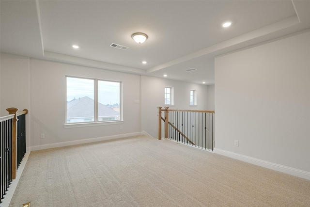 carpeted empty room with a raised ceiling