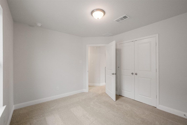 unfurnished bedroom featuring a closet and light carpet