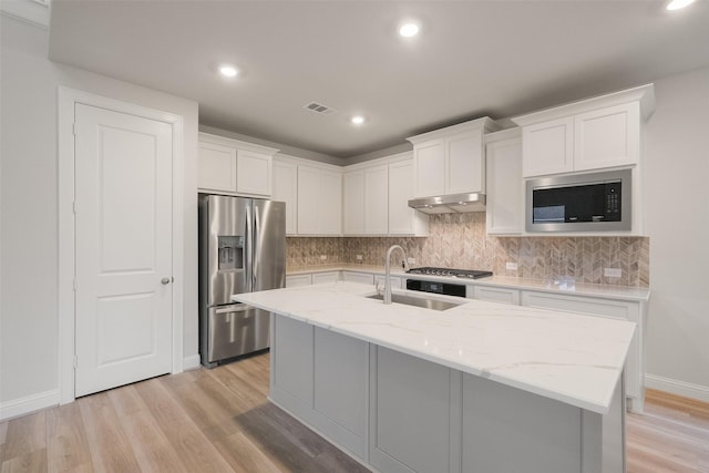 kitchen featuring white cabinets, a center island with sink, stainless steel refrigerator with ice dispenser, and built in microwave