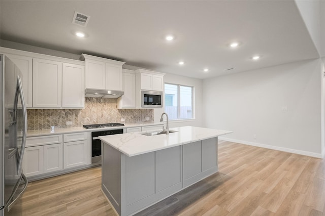 kitchen featuring sink, white cabinetry, light stone countertops, a center island with sink, and appliances with stainless steel finishes