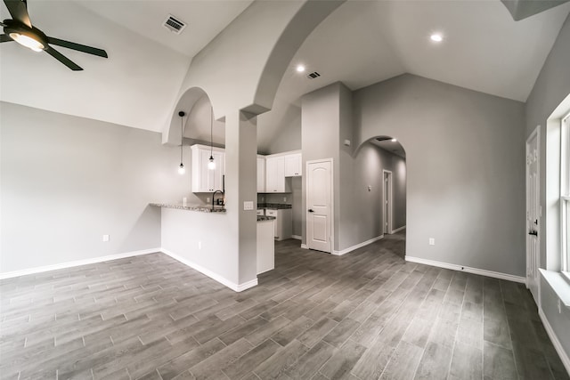 unfurnished living room featuring ceiling fan, sink, and high vaulted ceiling