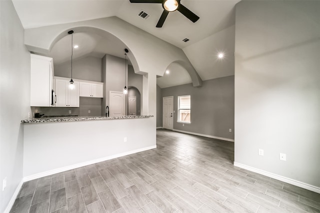 kitchen featuring white cabinetry, ceiling fan, light stone counters, lofted ceiling, and decorative light fixtures